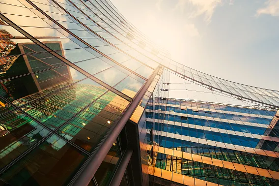 Futuristic glass office building in the golden sunlight, with blue sky above